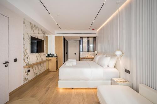 a white bedroom with a white bed and a couch at Ethereal White Resort Hotel & Spa - Adults Only in Heraklio Town