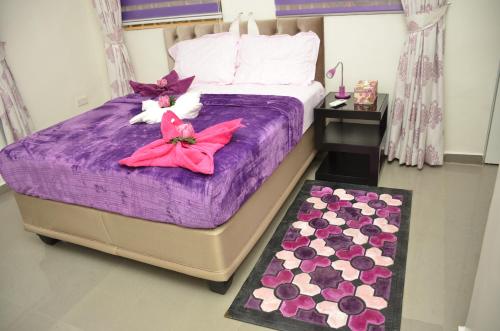 een slaapkamer met een bed met paarse lakens en bloemen bij SPA LAVENDER AND SUITES in Port Harcourt