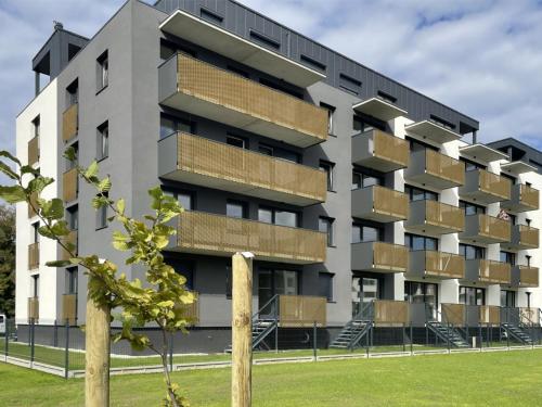 un edificio de apartamentos con balcones y un árbol en Apartament Diament 1 - Jezioro Nyskie, en Nysa