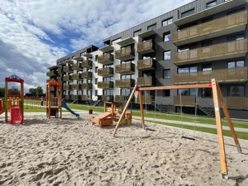 a playground in the sand in front of a building at Apartament Diament 1 - Jezioro Nyskie in Nysa