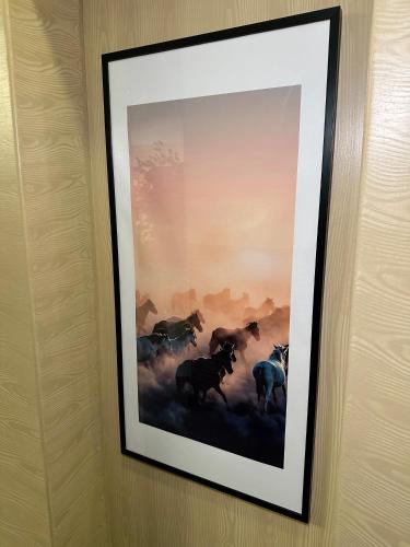 a framed picture of horses on a wall at PORT INN Hotel in Astana