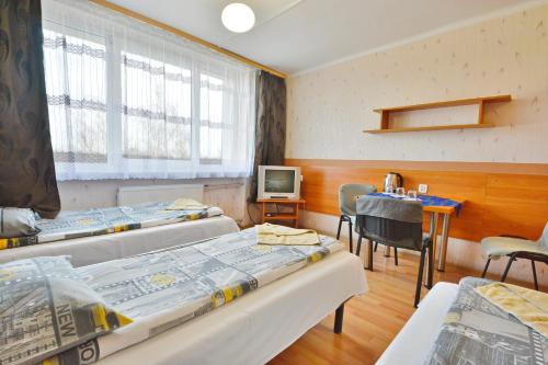 a room with four beds and a table and a television at Twój Hostel Ruda Śląska in Ruda Śląska