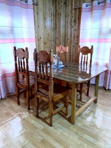 a wooden dining room table with four chairs and a wooden wall at The Ridge Homestay in Suryodaya