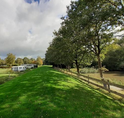 um campo de relva ao lado de uma vedação com uma caravana em Familiepark de Vechtvallei em Diffelen