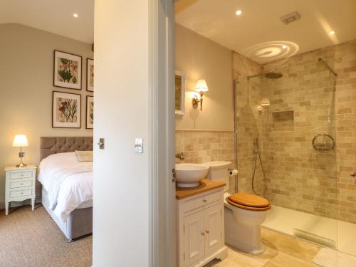 a bathroom with a bed and a sink and a shower at The Cottage in Yoxall