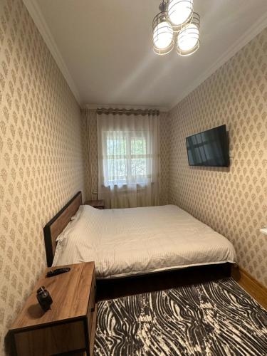 a small bedroom with a bed and a television at Your cozy apartment "Centro Parkside" in the City center in Samarkand