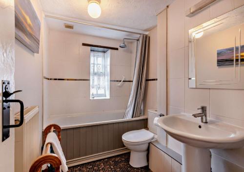 a bathroom with a sink and a toilet and a bath tub at Pitts Cottage in Brancaster