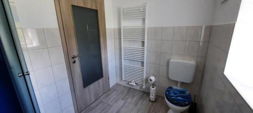 - une petite salle de bains avec des toilettes et une porte dans l'établissement Zum Jagdsteinblick, à Bahretal