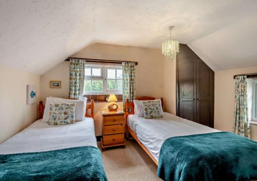 a bedroom with two beds and a window at Barmstone Cottage in Brancaster