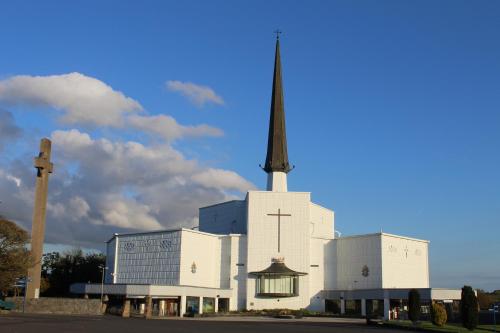 a large white church with a steeple and a cross at Heather Cottage and Shepherds Hut in Knock
