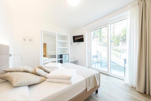 a white bedroom with two beds and a large window at Gabbiano in Malcesine