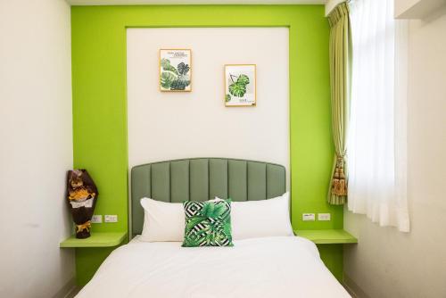 a bedroom with green walls and a bed at Welcome the sun enjoy the moon B&B in Kaohsiung