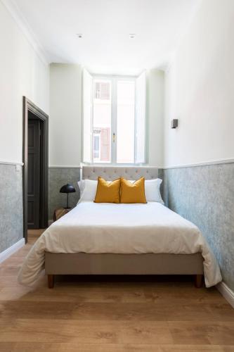 a bedroom with a large bed with two yellow pillows at Louly Spanish Steps in Rome