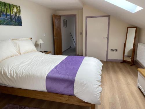 a bedroom with a large bed with a purple blanket at The Old Stables in Coleford