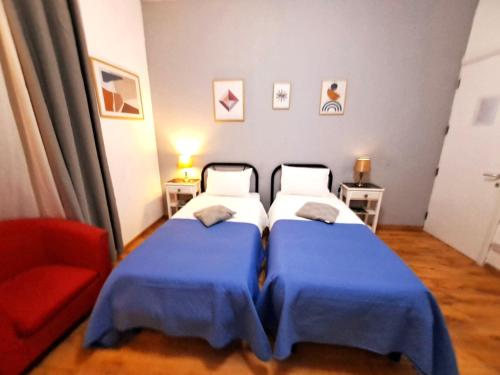 a bedroom with two beds and a red chair at Rotas B in St Julian's