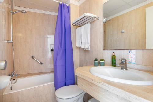 uma casa de banho com uma cortina de chuveiro azul e um lavatório. em Apartamentos Playa Marina em Cala Ferrera
