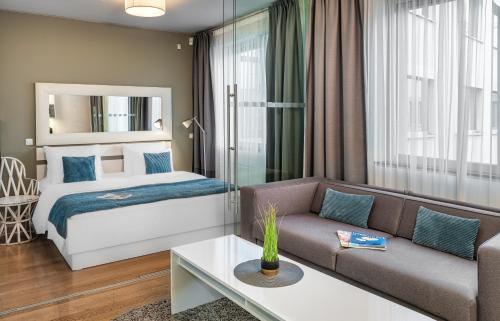 プラハにあるVN3 Terraces Suites by Adrezのベッドとソファ付きのホテルルーム