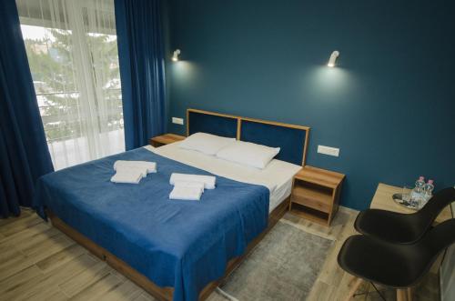 een slaapkamer met een bed met blauwe muren en een stoel bij Family Residence in Boekovel
