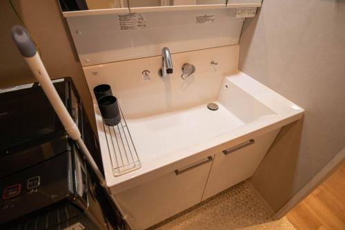 a sink in a small kitchen with aaucet at 浅草駅徒歩15分 2024年4月ニューオープン 2020年10月新築マンション 2023年12月リフォーム 43平米丸貸し切り ダブルベット2台と畳敷き布団2組 家庭式用品設備完備 202室 in Tokyo