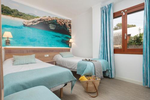 a room with two beds and a painting of a beach at Apartamentos Playa Marina in Cala Ferrera