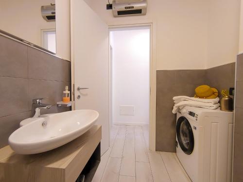 a bathroom with a sink and a washing machine at Dascio Paradise Ferienwohnung mit Dachterrasse am See in Dascio