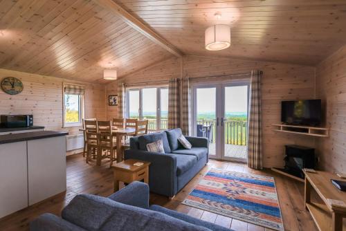 a living room with a couch and a tv and a table at Burgie Woodland Lodges in Forres