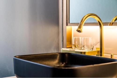 a kitchen sink with a gold faucet and glasses at Raffles Executive Apartment - Guangzhou Zhengjia Plaza Sports West Road StationBranch -Canton Fair Free Shuttle in Guangzhou