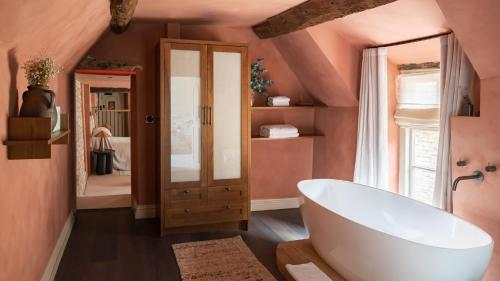 uma casa de banho com uma grande banheira branca e paredes cor-de-rosa em BULL Burford em Burford