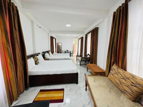 ein Hotelzimmer mit zwei Betten und einer Couch in der Unterkunft Shanthi Guest house in Diyatalawa