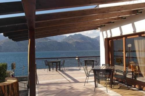 a deck with tables and chairs and a view of the water at Locanda Bellavista food&rooms in Malcesine