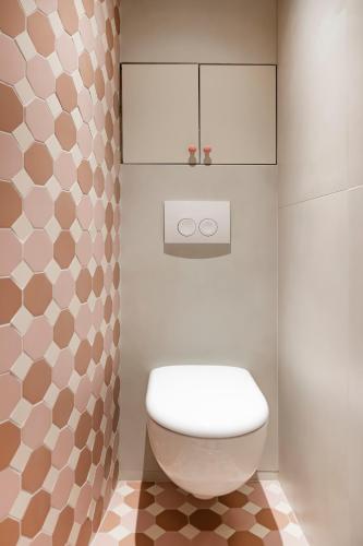 La salle de bains est pourvue de toilettes blanches et d'un mur. dans l'établissement Ile-Saint-Louis apartment, à Paris