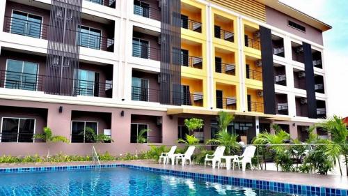 a hotel with a swimming pool in front of a building at B Space Residence in Nong Prue