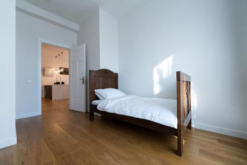 a bedroom with a bed with white sheets and wooden floors at Villa Langberg Spa in Ventspils