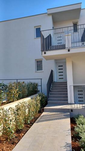 a white building with stairs and a balcony at Apartments Daria in Krk