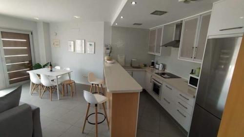 埃爾梅達諾的住宿－Los Martines el Medano，厨房配有白色橱柜和桌椅