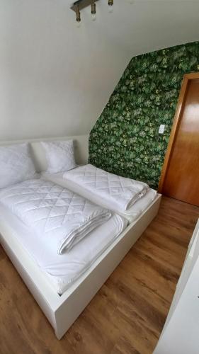 Cama blanca en habitación con pared verde en Ferienwohnung Dschungel en Emden