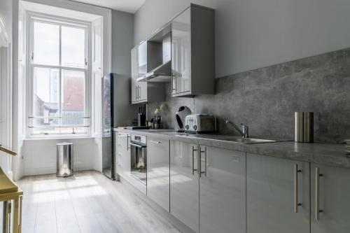 a kitchen with white cabinets and a window at Beautiful 4 bed flat in perfect central location in Glasgow