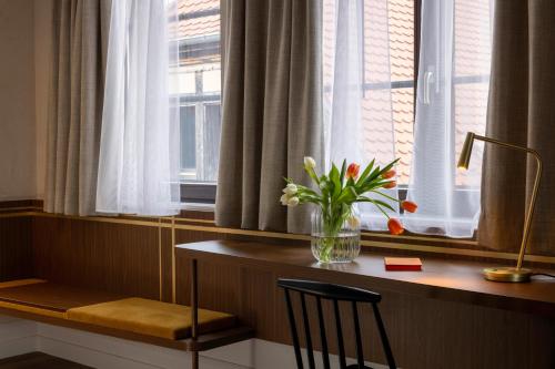 a desk with a vase of flowers on a window sill at Hotel Le Colombier in Obernai