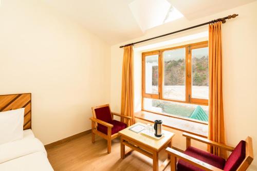 a room with a bed and a table and a window at Prakriti-The Retreat in Gangotri