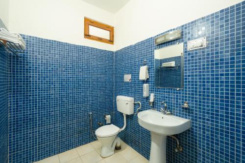a blue tiled bathroom with a toilet and a sink at Prakriti-The Retreat in Gangotri