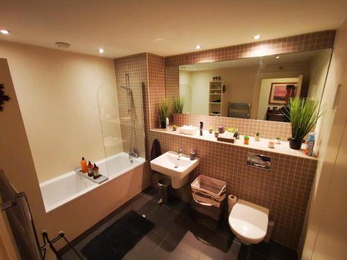 La salle de bains est pourvue d'un lavabo, de toilettes et d'une baignoire. dans l'établissement 2br Modern Luxury Loft Apartment, à Belfast
