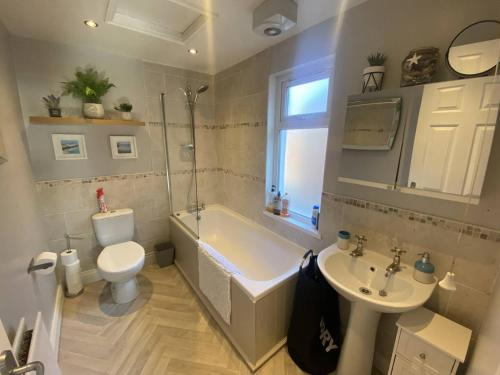 a bathroom with a tub and a toilet and a sink at 2br Cozy Duplex in Belfast