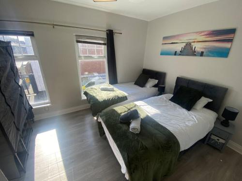 two beds in a room with two windows at 2br Cozy Duplex in Belfast