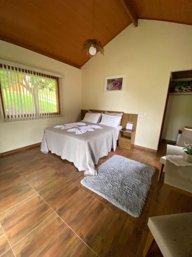 a bedroom with a bed and a large window at Pousada Irmãos Tonoli in Venda Nova do Imigrante