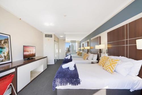 ein Schlafzimmer mit einem großen weißen Bett und einem TV in der Unterkunft Ocean View Surfers Paradise Studio Close to Beach in Gold Coast