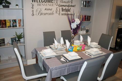 a dining room table with chairs and a table with books at 4 Bed Boutique House Lisburn Road in Belfast