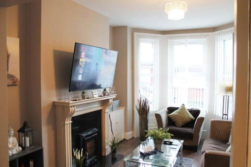 a living room with a fireplace and a flat screen tv at 4 Bed Boutique House Lisburn Road in Belfast