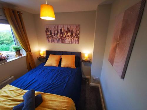 a bedroom with a bed with blue sheets and orange pillows at 4br Modern Botanic House in Belfast