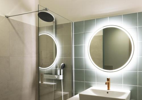 a bathroom with a sink and a mirror at Hood House Kassel - volldigitales Serviced Apartment in Kassel