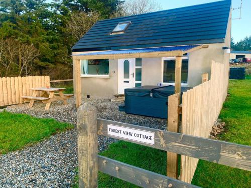 a small tiny house with a wooden fence at Forest View Cottage - Private Hot Tub in Ballynameen
